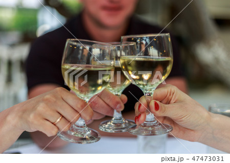 Pouring white wine into the glass against wooden table Pouring white wine into the glass against wooden table 47473031