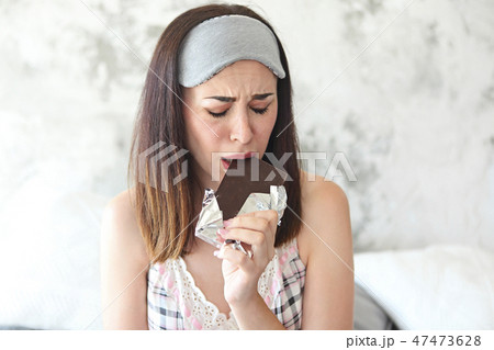 Cheerful sad young craing woman eating chocolate Cheerful sad young craing woman eating chocolate 47473628