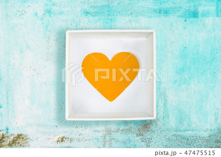 Yellow paper heart in white cardboard box on old turquoise metal background 47475515