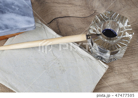 Quill pen and glass inkwell with old letters Quill pen and glass inkwell with old letters 47477505