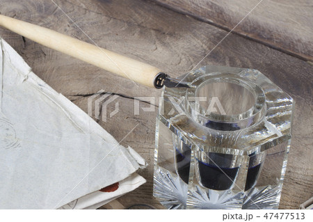 Quill pen and glass inkwell with old letters Quill pen and glass inkwell with old letters 47477513