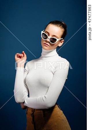 Portrait of a beautiful young girl in sunglasses on a blue background Portrait of a beautiful young girl in sunglasses on a blue background 47477863