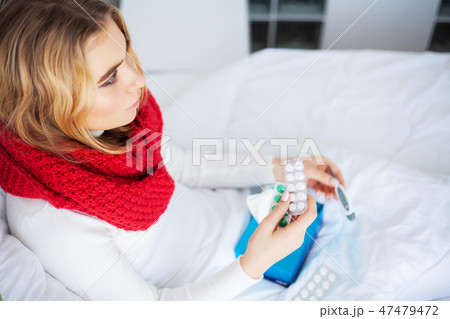 Sick Woman. Woman with flu virus lying in bed, she is measuring her temperature with a thermometer Sick Woman. Woman with flu virus lying in bed, she is measuring her temperature with a thermometer 47479472
