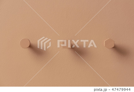 Metal orange hangers in forms of circle and square and hexagon on colorful wall in studio 47479944