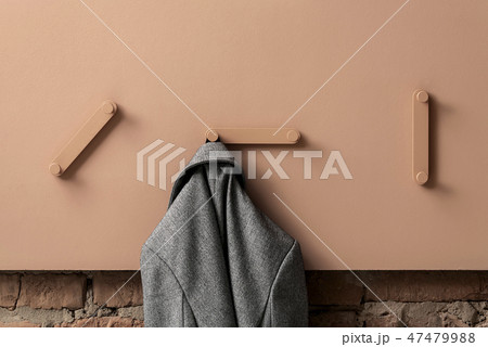 Fancy coral metal hangers with hanging gray jacket on colorful wall in studio 47479988