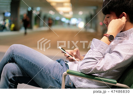 Young man enjoy using smart phone while waiting Young man enjoy using smart phone while waiting 47486830
