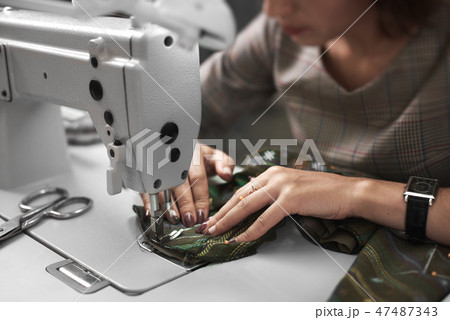 Seamstress working on modern electrical sewing machine making exclusive garments in fashion studio. 47487343