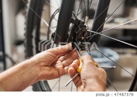 Male mechanic working in bicycle repair shop using tools Male mechanic working in bicycle repair shop using tools 47487376