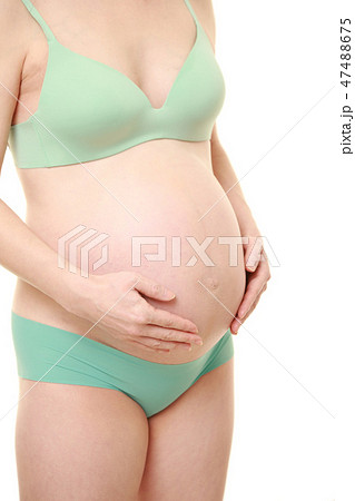 お腹を労わる下着姿の妊婦の写真素材