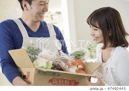 キッチンで届いた野菜を妻に見せる夫　産地直送　お取り寄せ 47492443