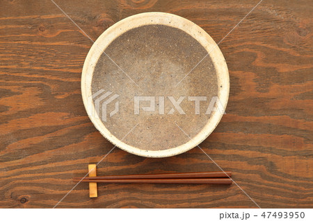 茶色いテーブルに置かれた土製の皿と箸 47493950