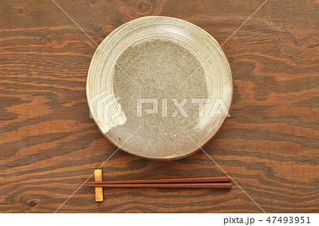 茶色いテーブルに置かれた土製の皿と箸 47493951