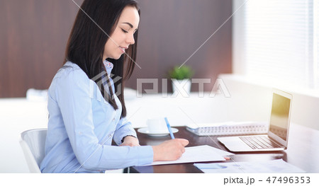 Young brunette business woman looks like a student girl working in office. Hispanic or latin 47496353