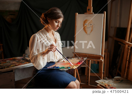 Female painter holds color palette and brush 47500421