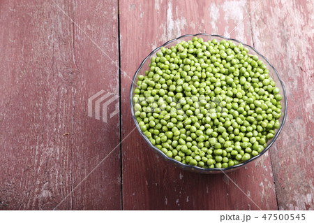 Peeled green peas in a plate on a wooden table. 47500545