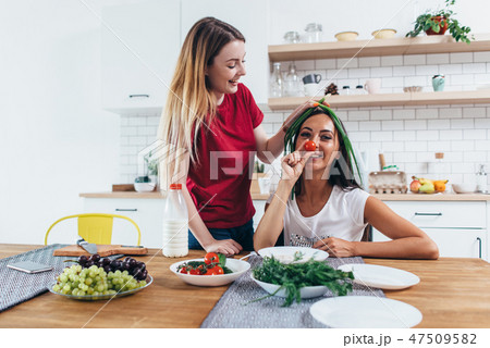 Girls fooling around in the kitchen playing with vegetables. 47509582