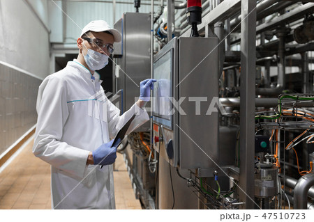 technologist taking necessary notes while standing at production department of dairy factory technologist taking necessary notes while standing at production department of dairy factory 47510723