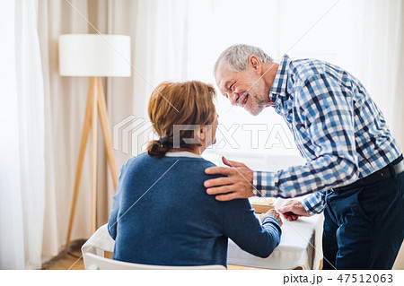 A senior couple sitting at the table at home, having breakfast. A senior couple sitting at the table at home, having breakfast. 47512063