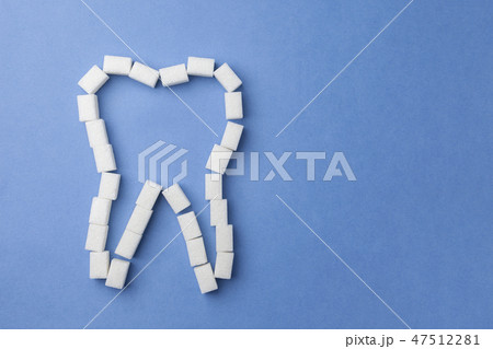 white tooth made of sugar on a blue background. The concept of oral health. 47512281