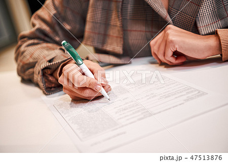 Businesswoman is fulfilling and signing contract with pen 47513876