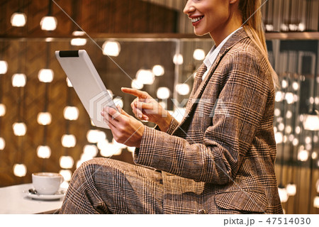 Cropped photo of woman using digital tablet while sitting at hotel restaurant 47514030