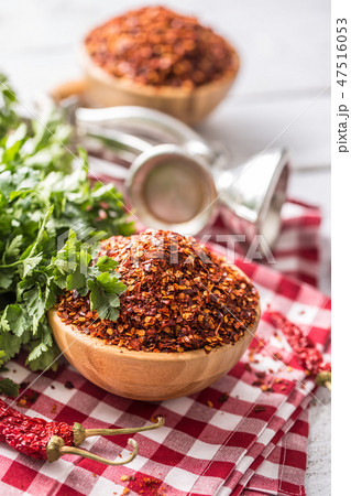 Dried and crushed chili peppers in wooden bowles. 47516053