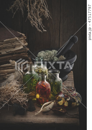 Essential oil bottles, mortar, books, dry roots. 47517797