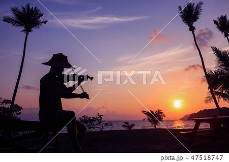 Asian man playing violin on the coconut beach Asian man playing violin on the coconut beach 47518747