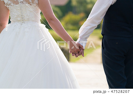 the newlyweds hold each other's hand and walk on a sunny day the newlyweds hold each other's hand and walk on a sunny day 47528207