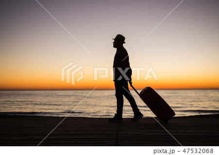 Relax man with suitcase on a beach at sunset silhouette. Holiday travel concept. Guy with suitcase Relax man with suitcase on a beach at sunset silhouette. Holiday travel concept. Guy with suitcase 47532068