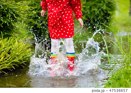 Kids in puddle in autumn rain. Waterproof wear Kids in puddle in autumn rain. Waterproof wear 47536657