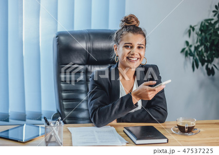 A young business stylish girl in the office is working on a laptop. During this time it is sitting 47537225