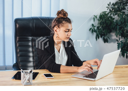 A young girl dressed in business clothes is working on a laptop. A young girl dressed in business clothes is working on a laptop. 47537720