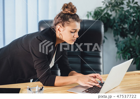 A young girl dressed in business clothes is working on a laptop. A young girl dressed in business clothes is working on a laptop. 47537722