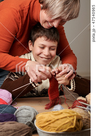 Mother is learning her child boy to knit.  47540965