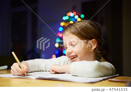 Inspired little girl at the table draw with crayons or do home work 47541535