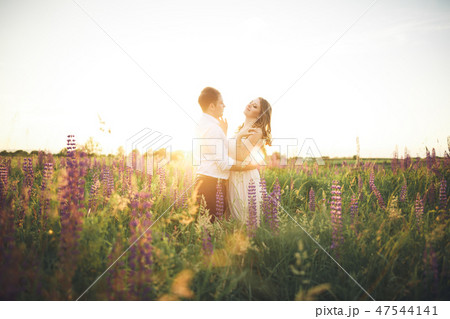 Emotional beautiful bride hugging newlywed groom from behind sunset at a field closeup Emotional beautiful bride hugging newlywed groom from behind sunset at a field closeup 47544141