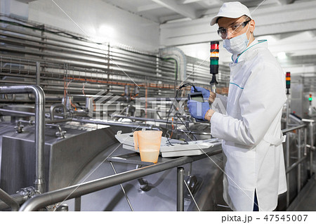 man in a mask and a Bathrobe connects the dosimeter to the dairy Plant 47545007
