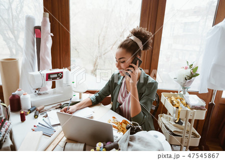 Young woman designer discussing new project. Young woman near sewing machine Young woman designer discussing new project. Young woman near sewing machine 47545867