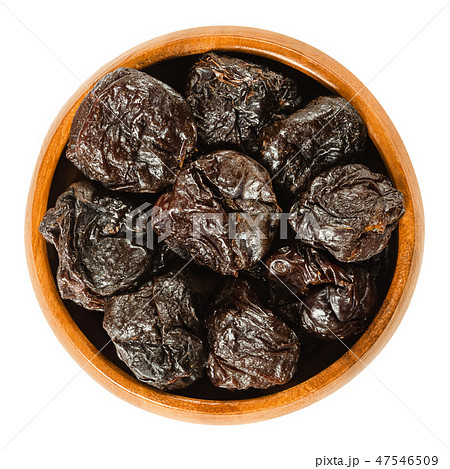 Prunes, dried plums in wooden bowl over white Prunes, dried plums in wooden bowl over white 47546509