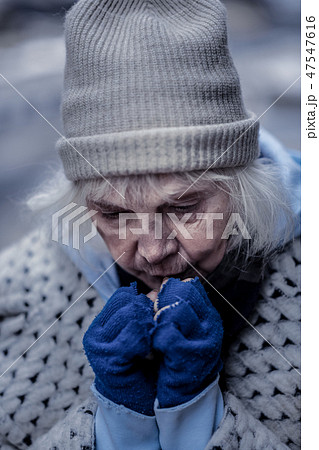 Depressed homeless woman trying to warm her hands 47547616