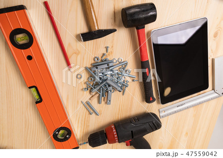 construction tool and a digital tablet lie on a light wooden table 47559042