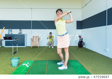 fit woman practicing golf swing during professional class indoors 47559697