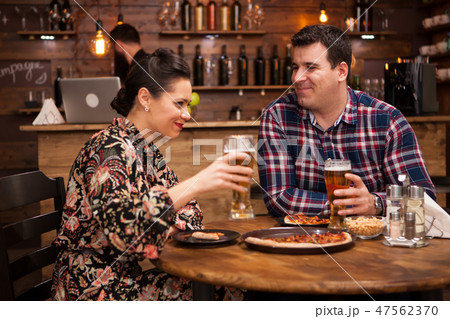 Couple relaxing at pub and eating pizza. 47562370