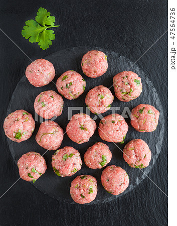 Uncooked raw meatballs on black cutting board 47564736