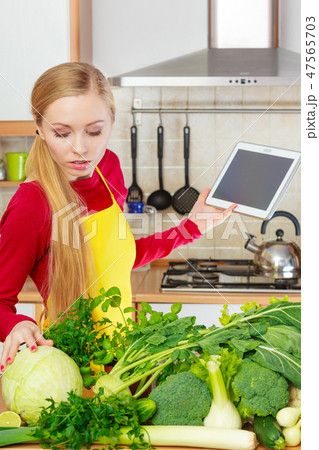 Woman in kitchen holding tablet 47565703