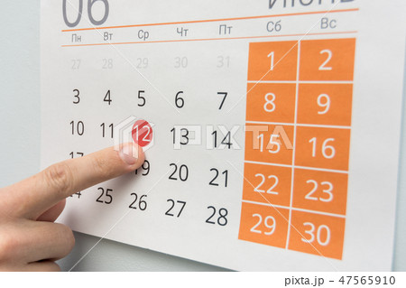Finger points to a holiday in the wall calendar Finger points to a holiday in the wall calendar 47565910
