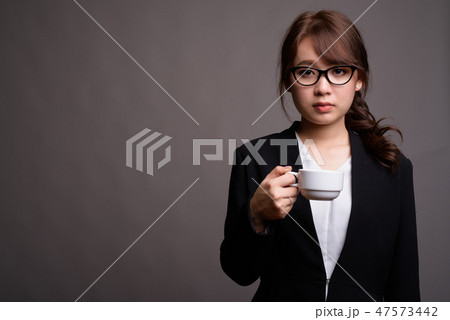 Young beautiful Asian businesswoman holding coffee cup Young beautiful Asian businesswoman holding coffee cup 47573442
