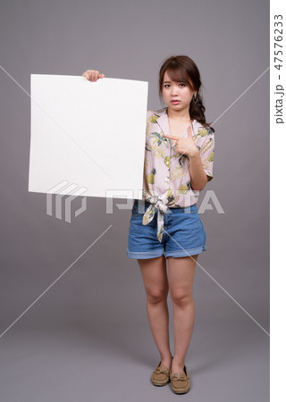 Asian woman holding empty white board with copyspace Asian woman holding empty white board with copyspace 47576233