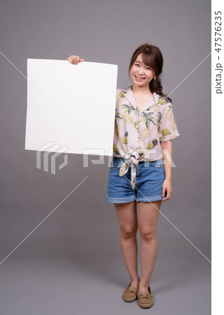 Asian woman holding empty white board with copyspace Asian woman holding empty white board with copyspace 47576235
